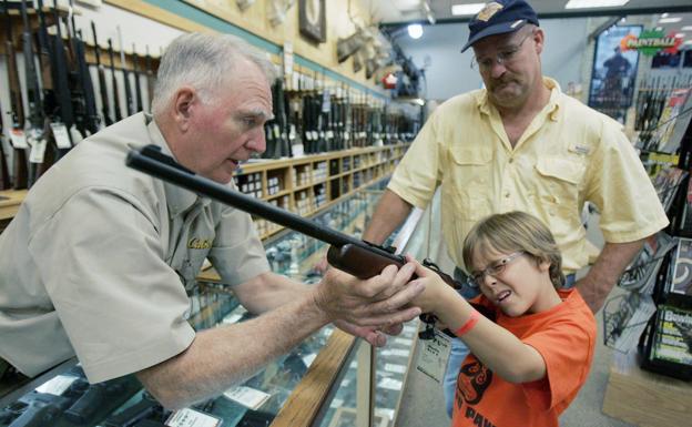Un niño, acompañado por su padre, prueba un rifle en una tienda de armas de Fort Worth (EE UU). Reuters